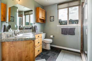 Bathroom with vanity, a stall shower, and stone finish floors