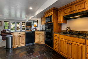 Kitchen featuring a peninsula, a textured ceiling, black appliances, under cabinet range hood, and open floor plan