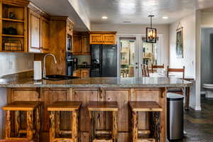 Kitchen with black appliances, recessed lighting, brown cabinets, a peninsula, and a textured ceiling