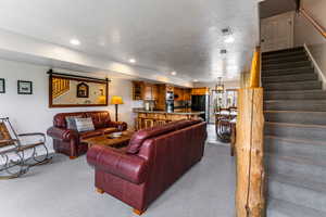 Living room with carpet, a textured ceiling, stairway, and recessed lighting