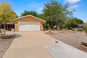 Ranch-style home with concrete driveway, brick siding, an attached garage, and stucco siding
