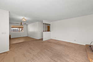 Unfurnished room featuring a textured ceiling, carpet floors, and a chandelier