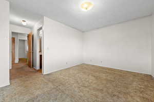 Unfurnished room featuring a textured ceiling and carpet