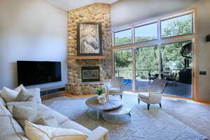Carpeted living room featuring high vaulted ceiling and a fireplace