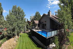 Back of property with a lawn, an outdoor pool, and a chimney