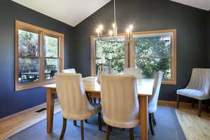 Dining area with a chandelier, vaulted ceiling, and wood finished floors