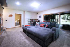 Carpeted living area featuring a textured ceiling and baseboards