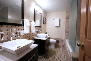 Full bathroom featuring a tile shower, a textured ceiling, vanity, tile walls, and tiled tub
