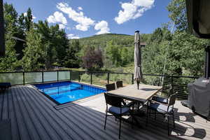 View of pool featuring outdoor dining space, a forest view, a grill, and a deck with mountain view