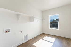 Washroom with washer hookup, electric dryer hookup, and wood finished floors