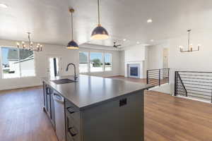 Kitchen with a chandelier, wood finished floors, a fireplace, a center island with sink, and recessed lighting