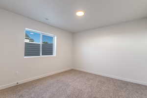 Spare room featuring carpet flooring and baseboards