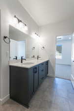 Bathroom with double vanity and baseboards
