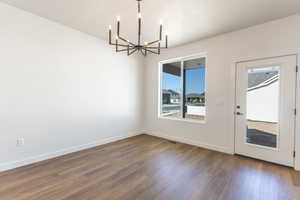 Unfurnished dining area featuring a chandelier and dark wood-style floors