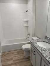 Full bath with tub / shower combination, vanity, and light wood-style flooring