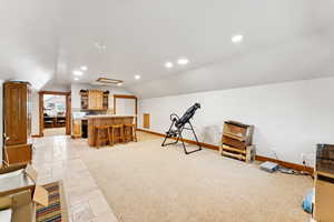 Exercise area with stone tile floors, lofted ceiling, recessed lighting, and a bar
