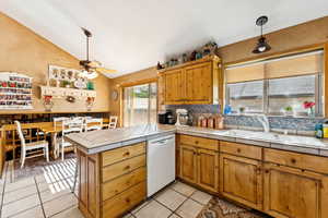 Kitchen with vaulted ceiling, a peninsula, a ceiling fan, decorative backsplash, and dishwasher