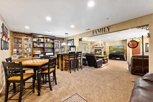 Carpeted dining area featuring recessed lighting and a stone fireplace