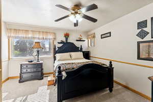 Carpeted bedroom with a textured ceiling and a ceiling fan