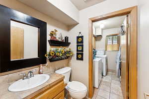 Bathroom with washer and clothes dryer, vanity, and tile patterned flooring