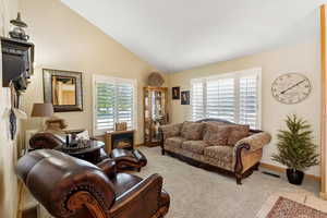 Living room featuring carpet flooring, high vaulted ceiling, and a fireplace