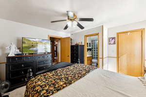 Bedroom with a textured ceiling, a ceiling fan, connected bathroom, and carpet flooring