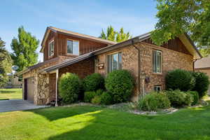 View of front of home featuring driveway, a front lawn, brick siding, and a garage