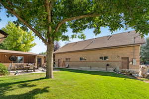 Rear view of house featuring roof with shingles, a yard, and a patio area
