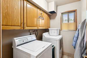 Laundry area with cabinet space, washer and clothes dryer, and a textured ceiling