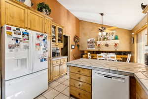 Kitchen featuring white appliances, lofted ceiling, tile counters, ceiling fan, and glass insert cabinets