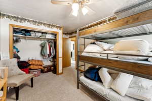Bedroom with light carpet, a closet, and ceiling fan