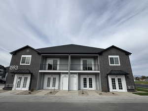 Traditional-style house featuring a standing seam roof, french doors, a metal roof, and a balcony