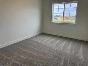 Carpeted spare room with baseboards