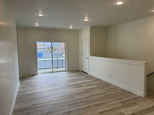 Empty room featuring light wood-style floors, a textured ceiling, and recessed lighting