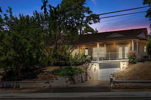 View of front of house with french doors, a garage, stucco siding, driveway, and a porch