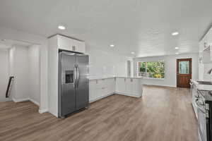 Kitchen with appliances with stainless steel finishes, recessed lighting, a peninsula, white cabinetry, and light countertops