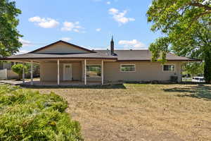 Rear view of property with a shingled roof, a patio area, a lawn, and a carport