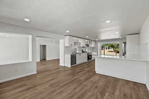 Kitchen with stainless steel appliances, white cabinetry, light countertops, recessed lighting, and a textured ceiling