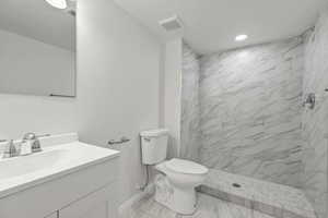 Full bath with vanity, a marble finish shower, and a textured ceiling