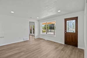 Foyer entrance featuring a textured ceiling, recessed lighting, and light wood-style flooring