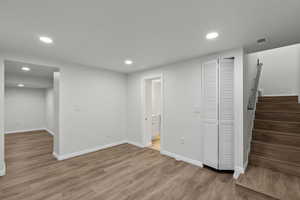 Basement with recessed lighting, light wood finished floors, and stairs