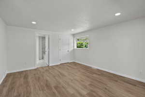 Unfurnished bedroom featuring wood finished floors, a textured ceiling, recessed lighting, and connected bathroom