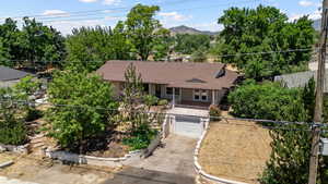 View of front facade with concrete driveway, a mountain view, roof with shingles, a garage, and french doors