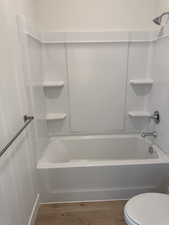 Bathroom with light wood-type flooring and bathtub / shower combination