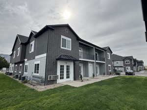 Rear view of house featuring a lawn, french doors, a standing seam roof, and a balcony