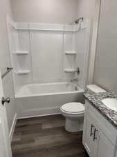 Full bath with bathtub / shower combination, vanity, and dark wood-style floors