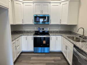 Kitchen with stainless steel appliances, light stone counters, and white cabinetry