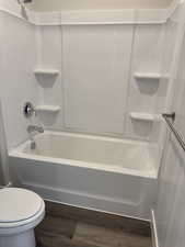 Bathroom featuring dark wood finished floors and  shower combination