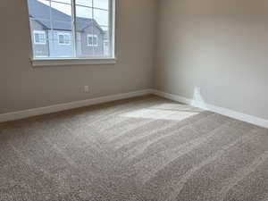 Carpeted spare room featuring baseboards