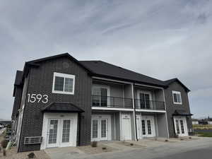 Back of property featuring a balcony, a standing seam roof, brick siding, a metal roof, and french doors